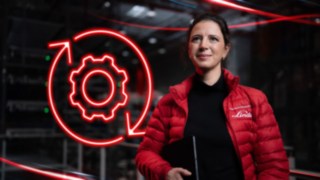 Mitarbeiterin von Linde Material Handling in einer Lagerhalle mit rotem LED-Symbol eines Zahnrads im Hintergrund.